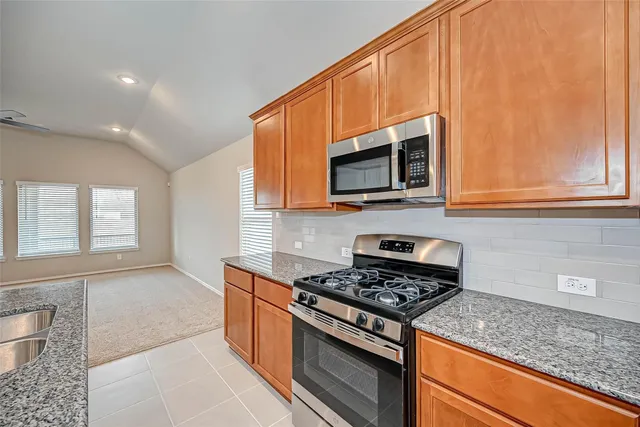 a kitchen with stainless steel appliances granite countertop a stove microwave and sink