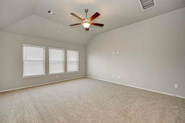 an empty room with ceiling fan and windows