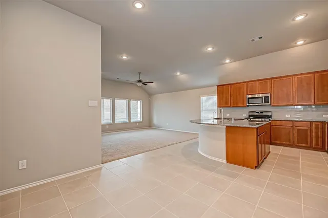 a large kitchen with stainless steel appliances granite countertop a stove a sink and a refrigerator