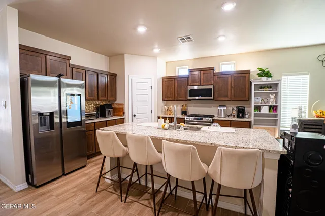 a kitchen with stainless steel appliances granite countertop a refrigerator a stove a sink a dining table and chairs