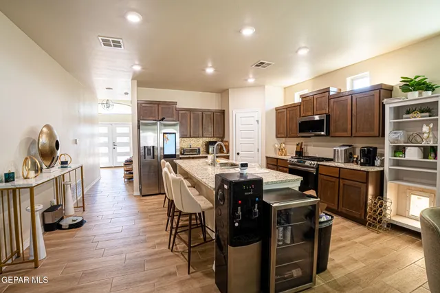 a kitchen with stainless steel appliances a table chairs refrigerator and a sink
