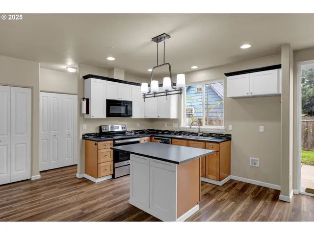 a kitchen with granite countertop a stove top oven a sink dishwasher and a refrigerator with wooden floor