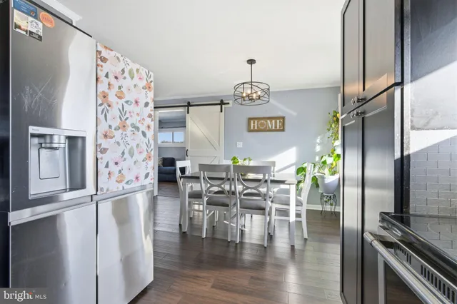 a kitchen with stainless steel appliances refrigerator dining table and chairs