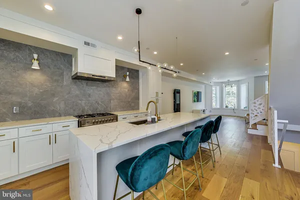a kitchen with stainless steel appliances granite countertop a stove a sink a oven a dining table and chairs with wooden floor