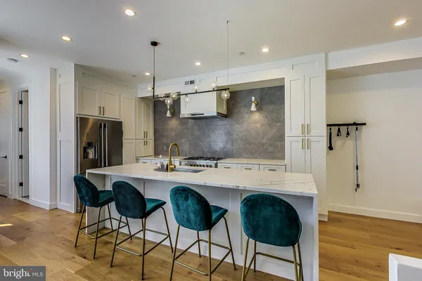 a kitchen with stainless steel appliances kitchen island granite countertop a sink a stove a refrigerator and island with wooden floor
