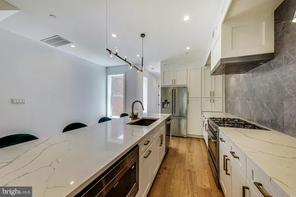 a kitchen with stainless steel appliances a sink a stove a refrigerator and cabinets