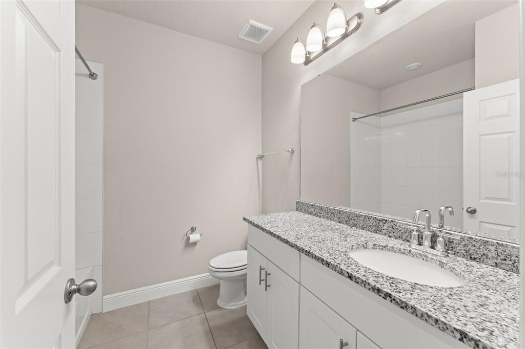 2224 Shadowland Loop Winter Park, FL 32792 - Photo 32 of 42 a bathroom with a granite countertop sink a toilet and a mirror