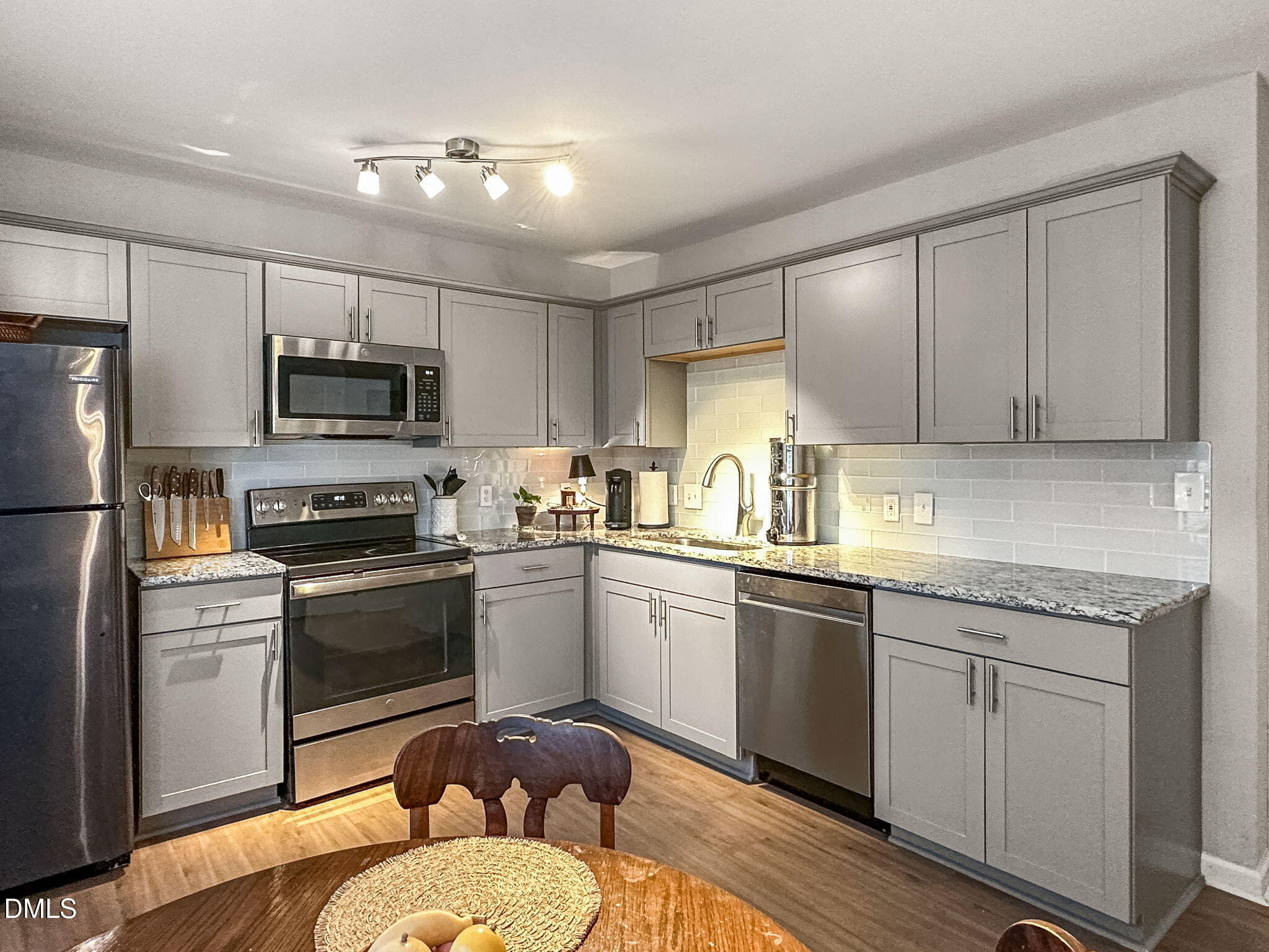 1019 Parkthrough Street Cary, NC 27511 - Photo 7 of 23 a kitchen with kitchen island granite countertop a sink stainless steel appliances and white cabinets