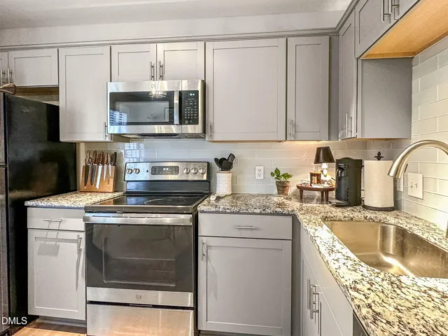 a kitchen with stainless steel appliances granite countertop a stove a sink and a microwave