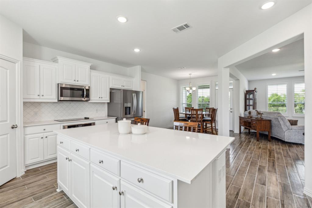 2410 Black Jack Oak Road Terrell, TX 75161 - Photo 12 of 31 Kitchen with stainless steel appliances, light wood-type flooring, a kitchen island, light countertops, and tasteful backsplash