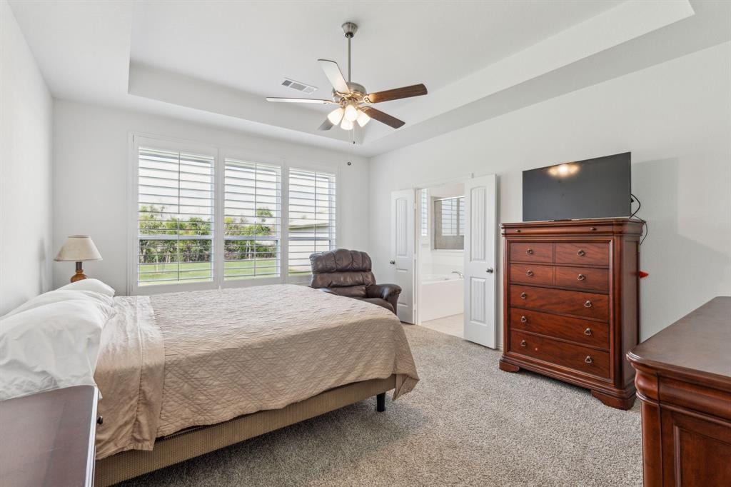 2410 Black Jack Oak Road Terrell, TX 75161 - Photo 15 of 31 Bedroom featuring a tray ceiling, light colored carpet, ensuite bath, and a ceiling fan