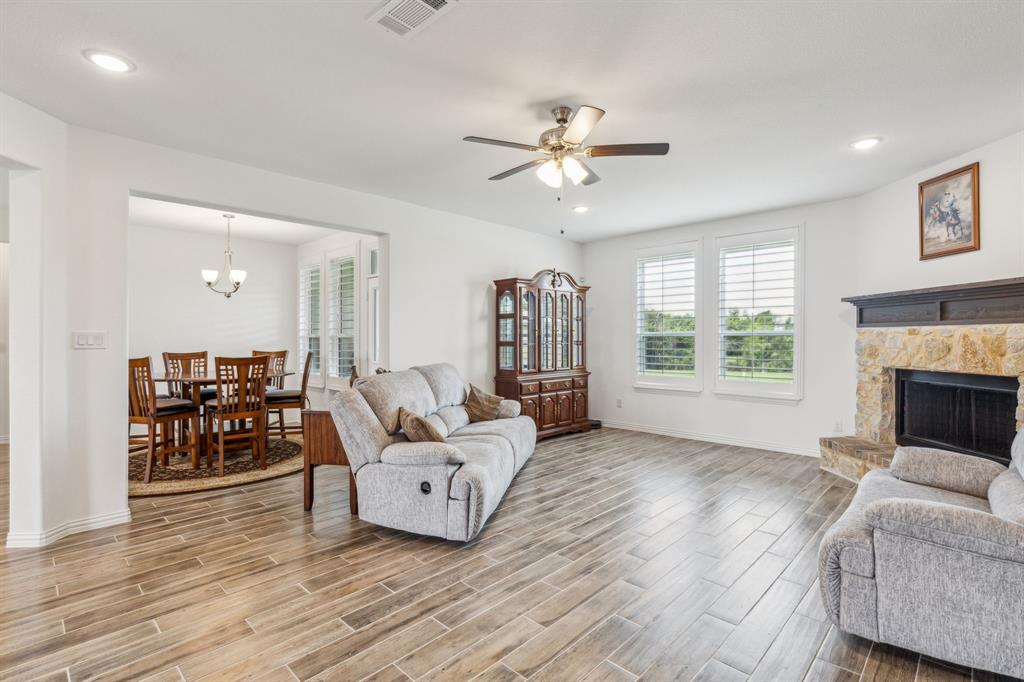 2410 Black Jack Oak Road Terrell, TX 75161 - Photo 16 of 31 Living area with light wood-style floors, ceiling fan, a stone fireplace, a chandelier, and baseboards