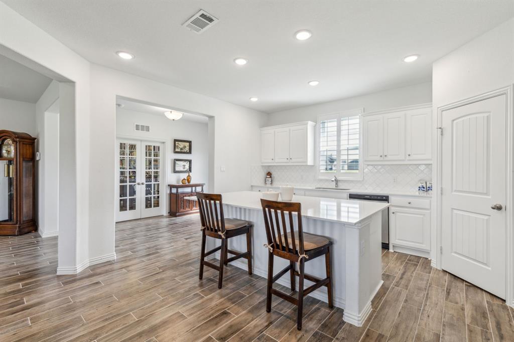 2410 Black Jack Oak Road Terrell, TX 75161 - Photo 10 of 31 Kitchen featuring stainless steel dishwasher, a sink, light wood finished floors, a kitchen breakfast bar, and light countertops