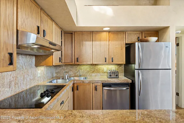 a kitchen with stainless steel appliances granite countertop a refrigerator a sink and a stove