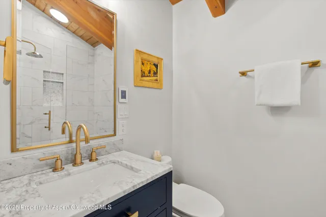 a bathroom with a granite countertop sink and a toilet