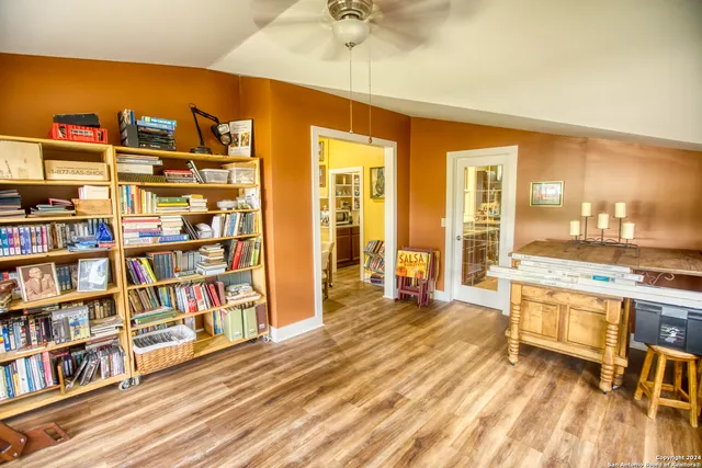 a living room with stainless steel appliances lots of furniture and a book shelf
