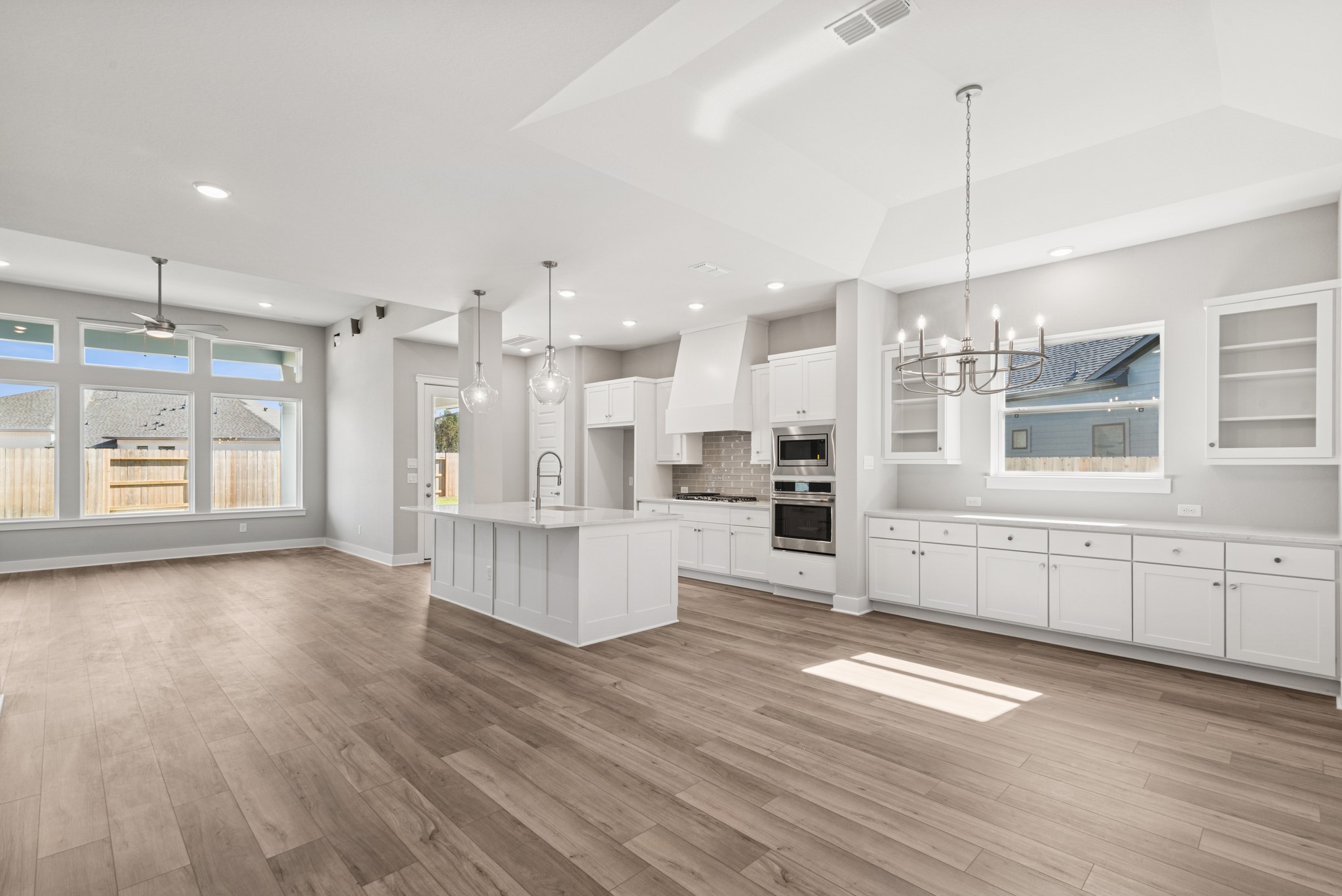 18623 Rumba Court Conroe, TX 77302 - Photo 25 of 48 a large kitchen with kitchen island a stove a refrigerator a sink dishwasher and white cabinets with wooden floor