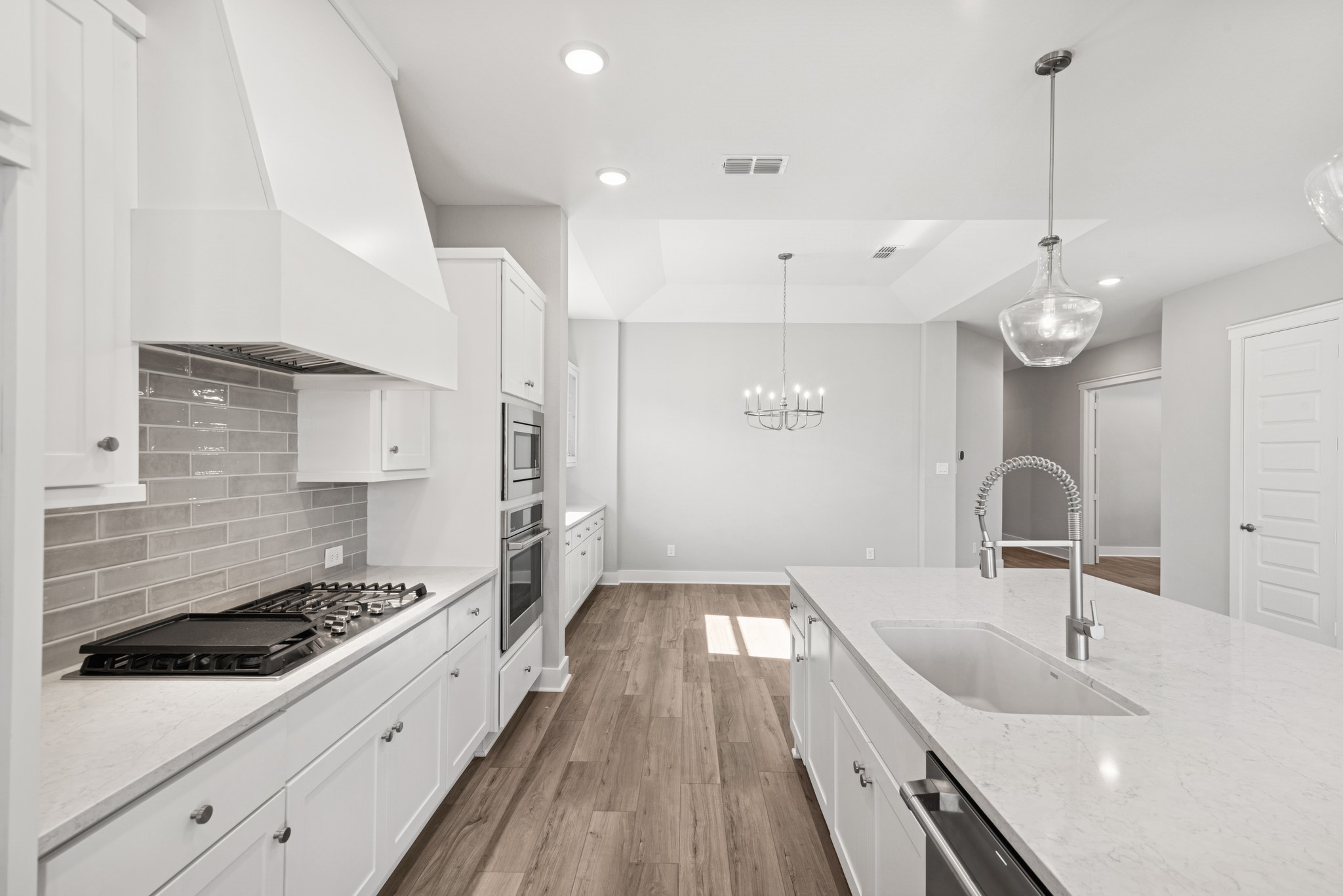 18623 Rumba Court Conroe, TX 77302 - Photo 28 of 48 a large kitchen with kitchen island a stove a sink a center island and wooden floor