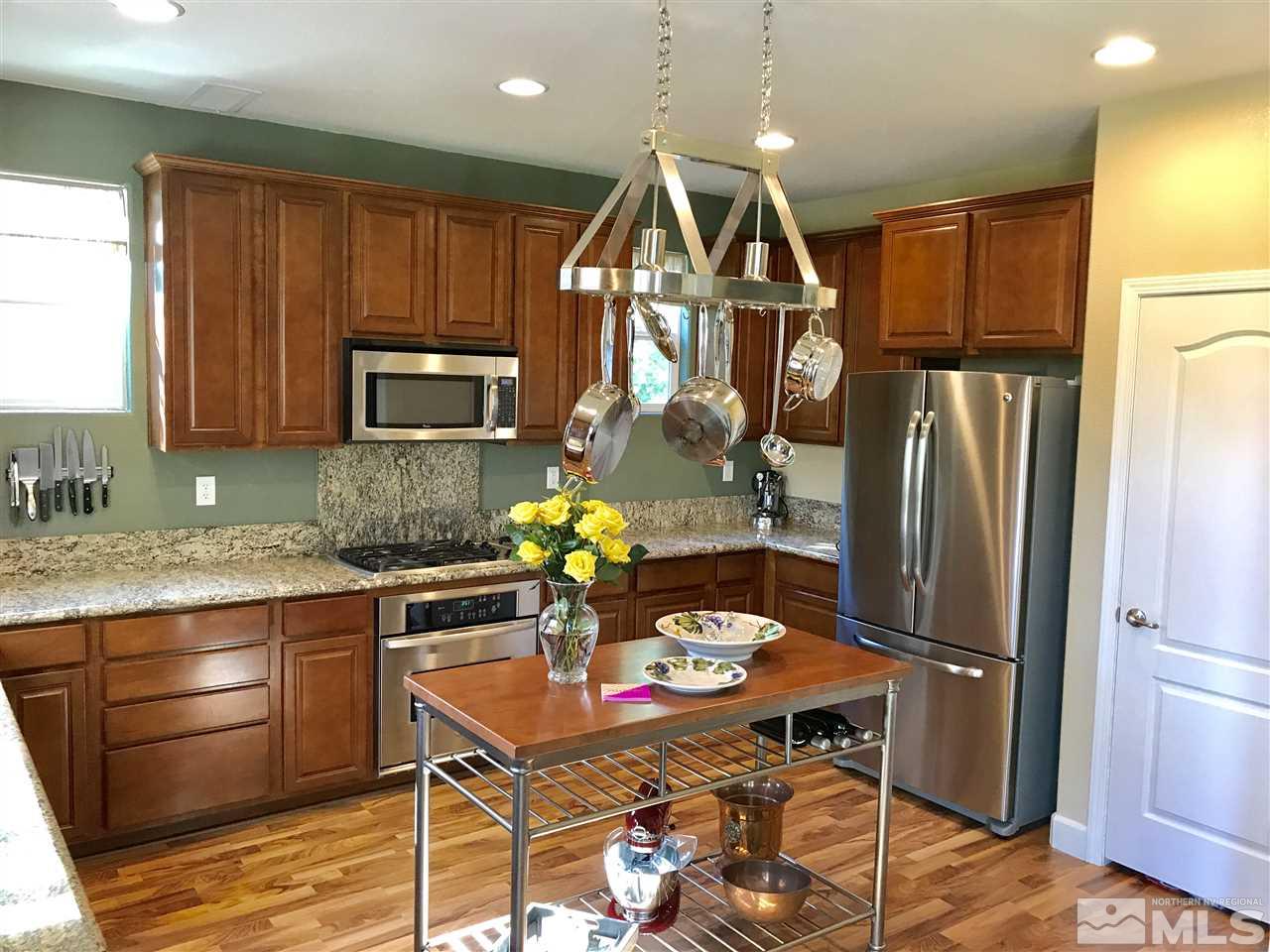 495 Terracina Way Reno, NV 89521 - Photo 3 of 25 a kitchen with stainless steel appliances granite countertop a refrigerator a stove top oven a sink dishwasher and wooden cabinets with wooden floor