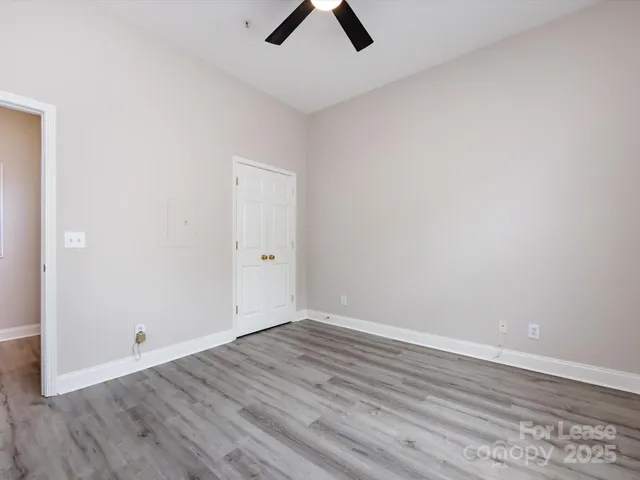 an empty room with ceiling fan and window