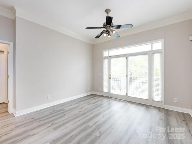 a view of empty room with wooden floor and fan