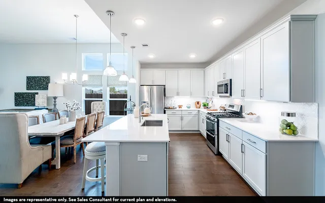 a large white kitchen with lots of counter space a sink appliances and cabinets