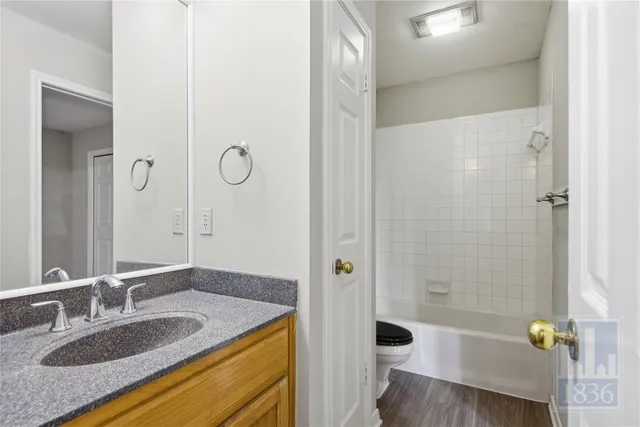 a bathroom with a granite countertop sink a toilet and shower