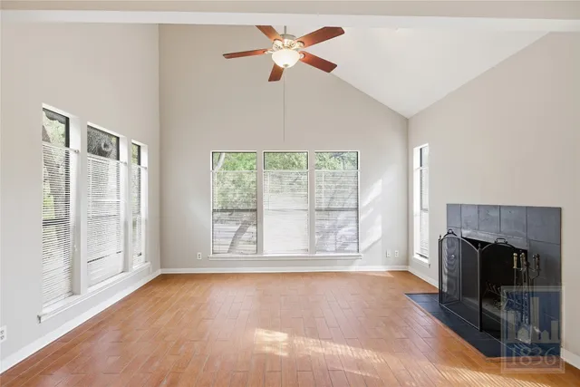 an empty room with fireplace fan and windows