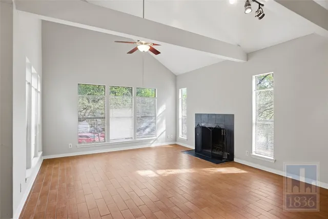 an empty room with wooden floor fireplace and windows
