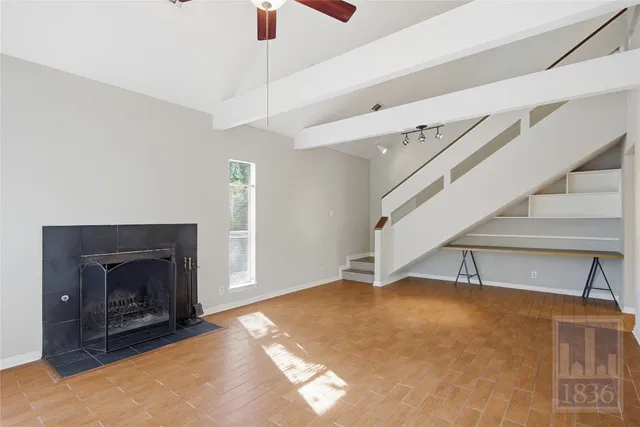 a view of an empty room with wooden floor fireplace and a window