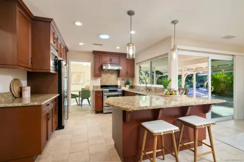 a kitchen with stainless steel appliances granite countertop wooden cabinets a dining table and chairs