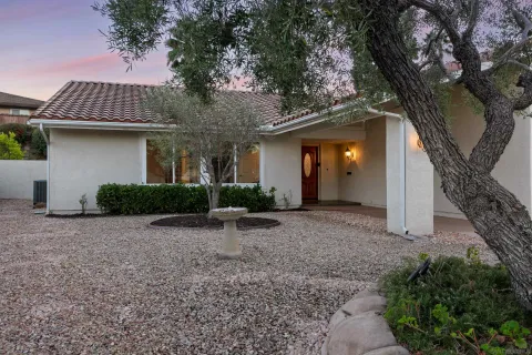 a view of a house with large tree and wooden fence