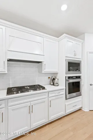 a kitchen with white cabinets and appliances