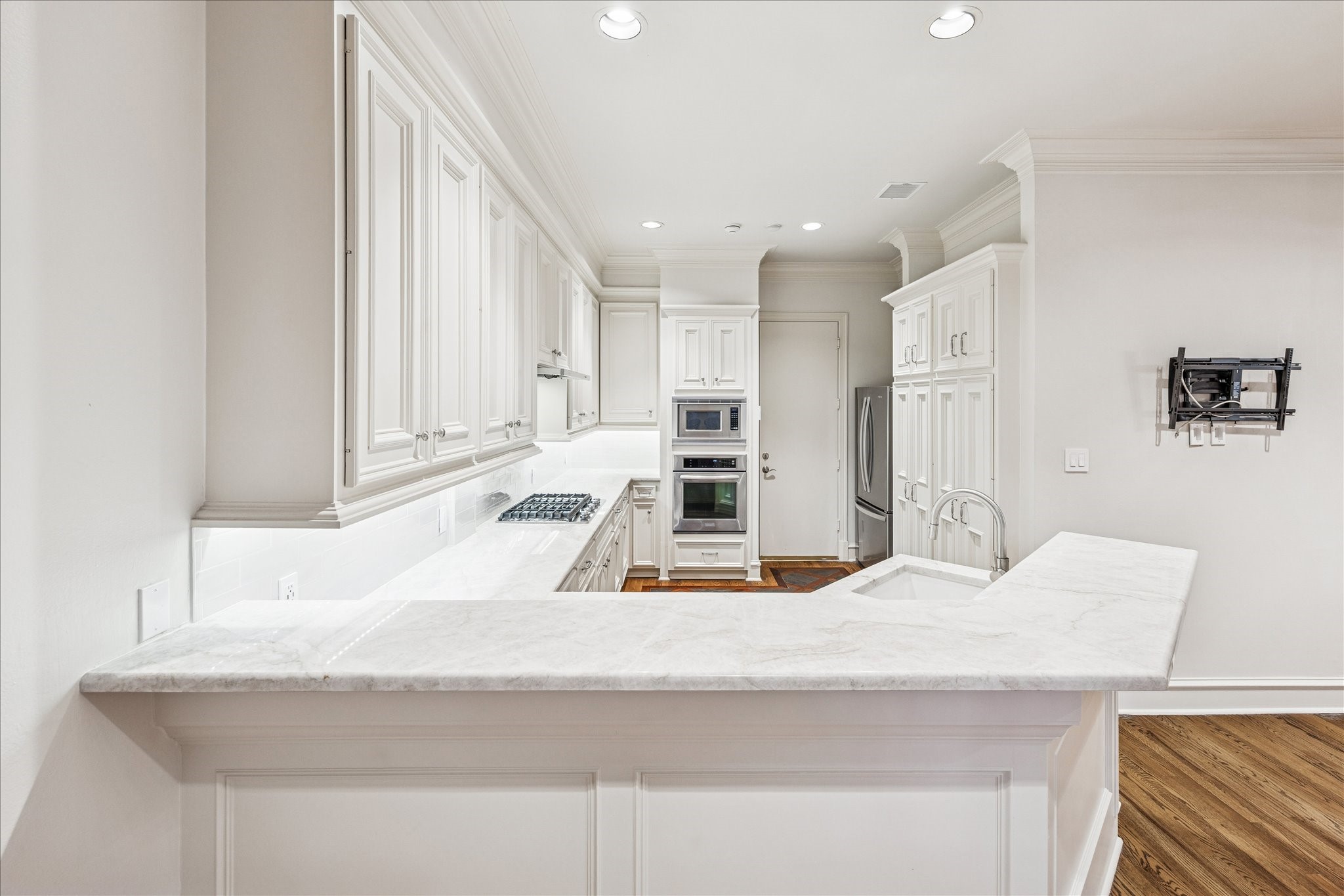 5823 Augusta Court Houston, TX 77057 - Photo 14 of 44 This kitchen features a bright, open layout with white cabinetry and quartz countertops. It includes built-in appliances, a modern gas cooktop, and ample storage.