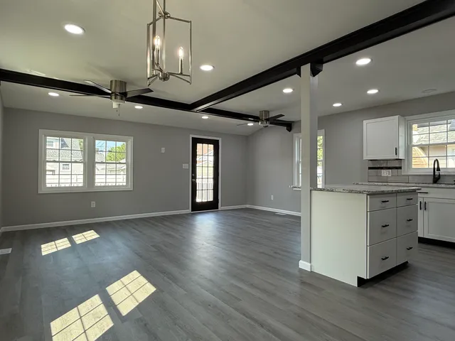 a view of an empty room with window and wooden floor