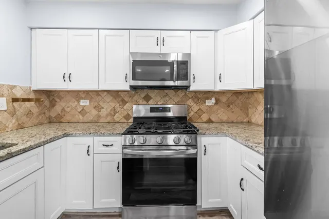 a kitchen with granite countertop white cabinets and stainless steel appliances