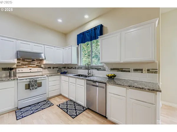 a kitchen with granite countertop white cabinets and white appliances