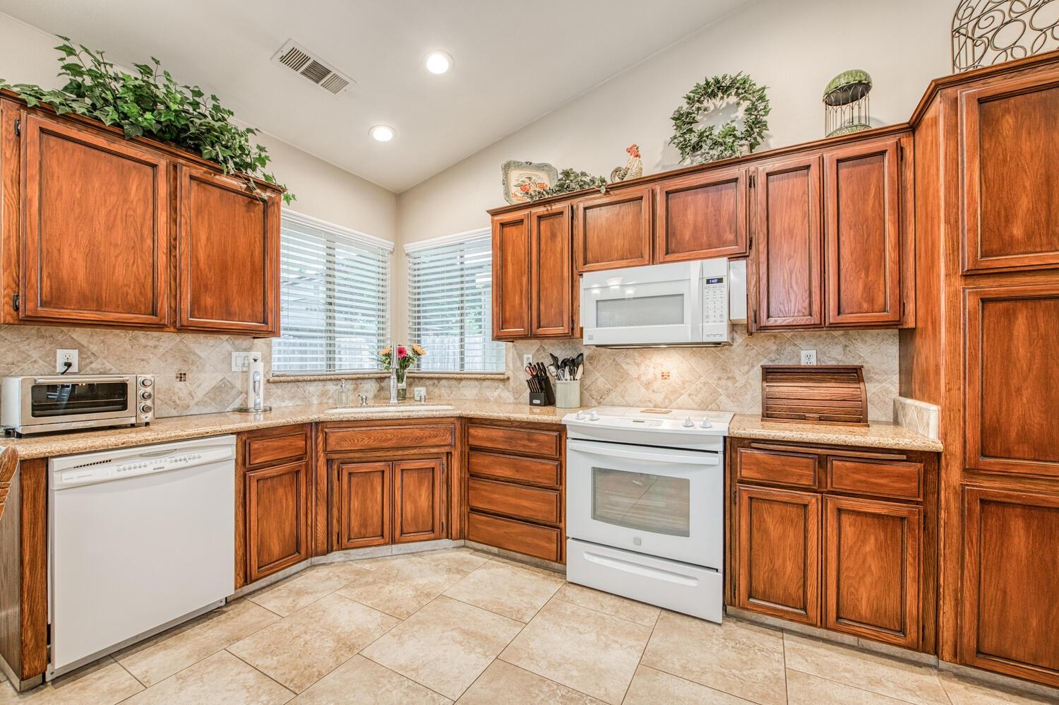 2512 Keats Avenue Clovis, CA 93611 - Photo 21 of 39 a kitchen with kitchen island granite countertop wooden cabinets and white appliances
