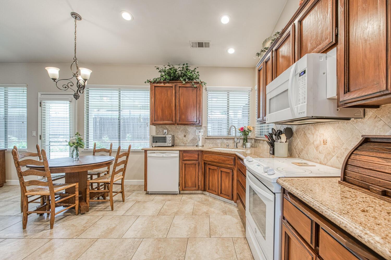 2512 Keats Avenue Clovis, CA 93611 - Photo 22 of 39 a kitchen with kitchen island granite countertop lots of white cabinets stainless steel appliances dining table and chairs