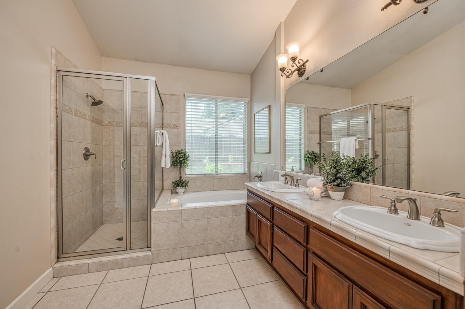 2512 Keats Avenue Clovis, CA 93611 - Photo 32 of 39 a spacious bathroom with a double vanity sink a large mirror and a bathtub with shower