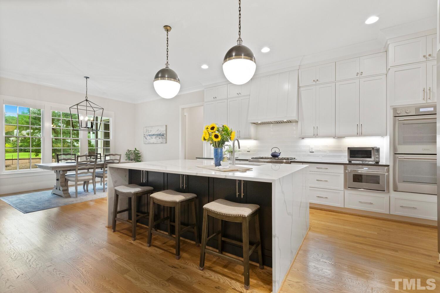 5105 Bella Ridge Drive Raleigh, NC 27615 - Photo 13 of 60 a kitchen with stainless steel appliances granite countertop a sink a stove a dining table chairs and chandelier