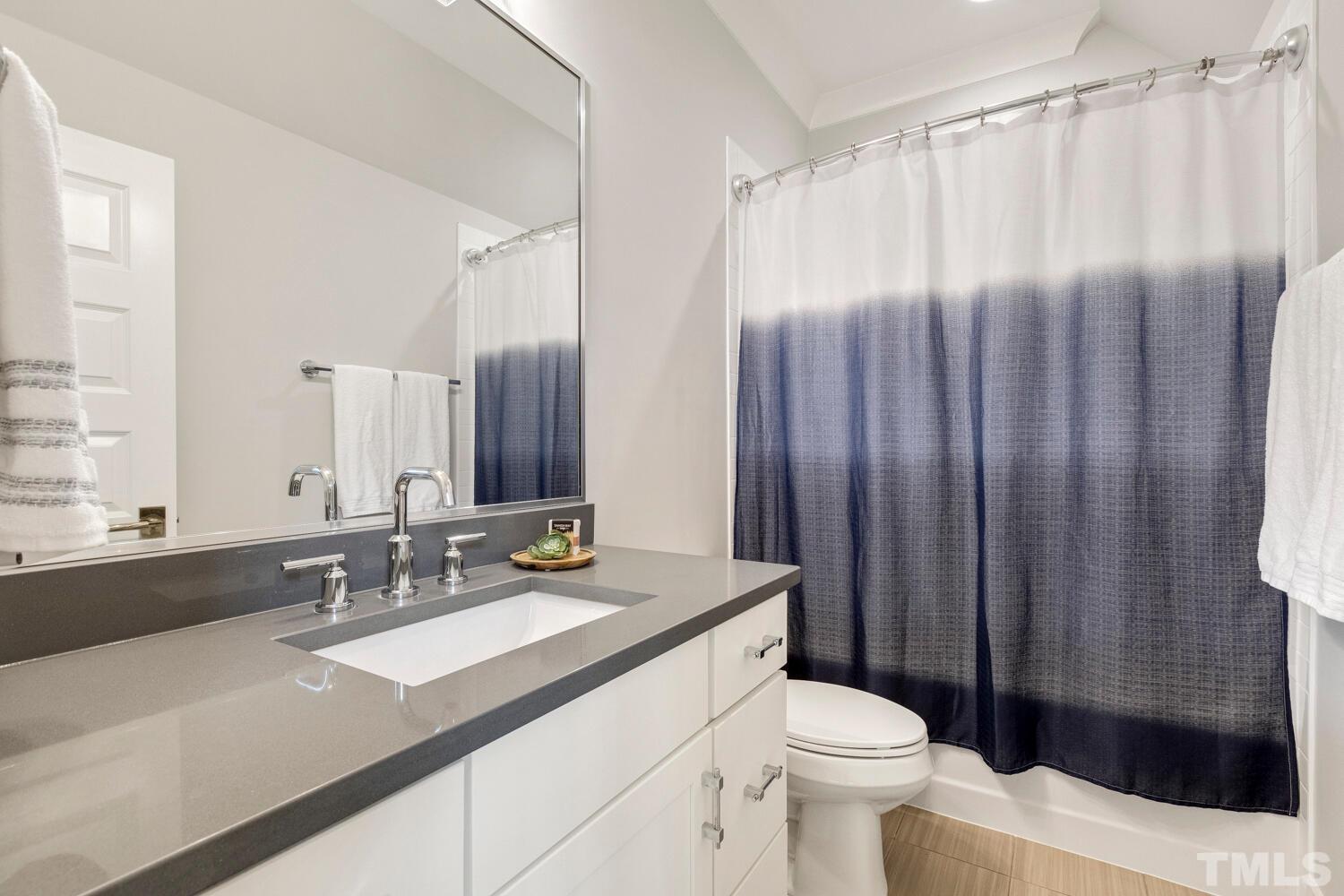 5105 Bella Ridge Drive Raleigh, NC 27615 - Photo 49 of 60 a bathroom with a sink a toilet a mirror and shower curtain