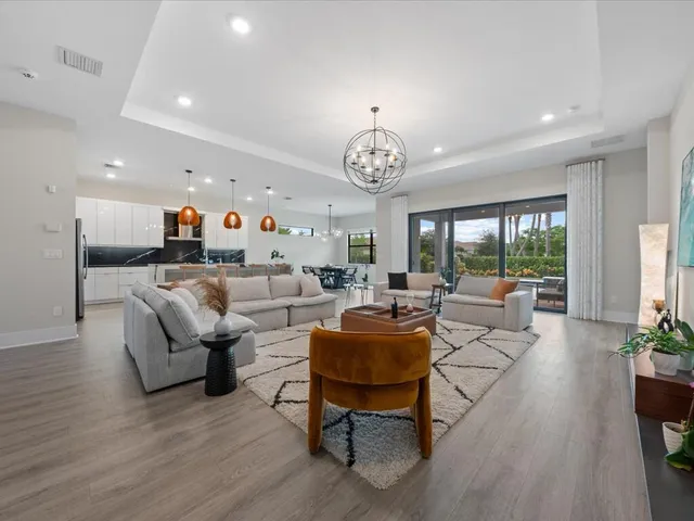 a living room with furniture kitchen view and a chandelier