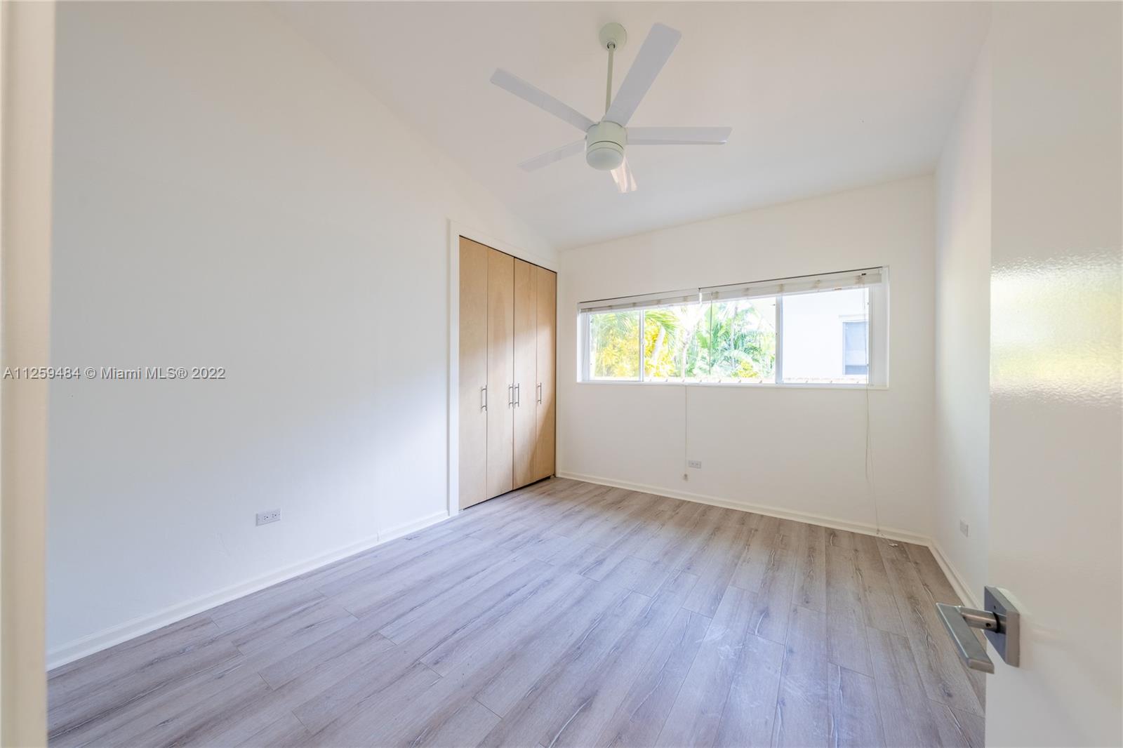 8810 Dickens Avenue Surfside, FL 33154 - Photo 9 of 15 an empty room with wooden floor chandelier fan and windows