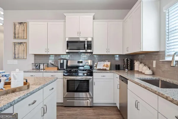 a kitchen with granite countertop white cabinets white stainless steel appliances and sink