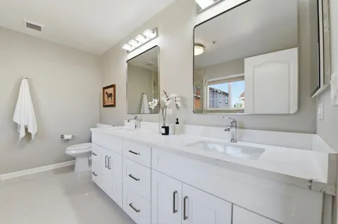 a bathroom with a granite countertop sink mirror vanity and toilet