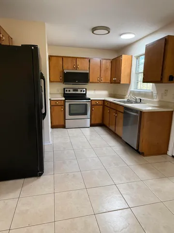 a kitchen with granite countertop a refrigerator and a stove top oven