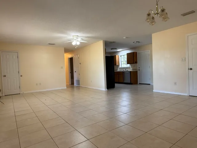 a view of empty room with kitchen and window