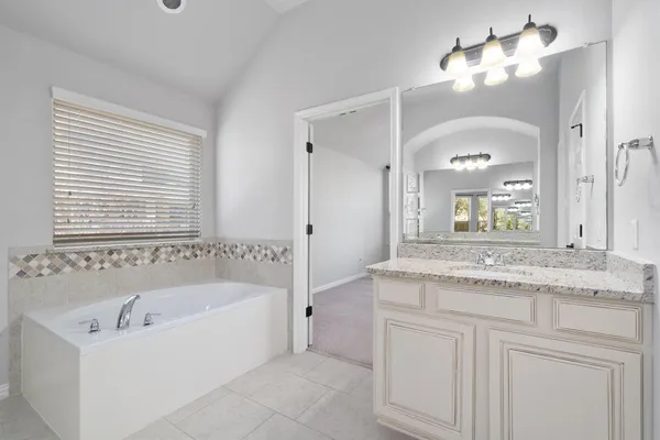 a bathroom with a granite countertop sink a mirror a bathtub and shower