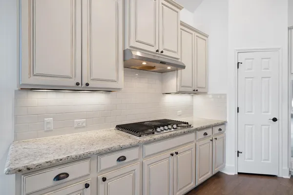 a kitchen with granite countertop white cabinets and a stove